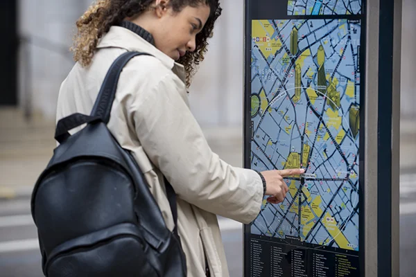 Passenger viewing a clear transport interchange map showing routes, walking connections and local facilities